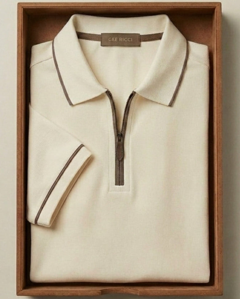 Folded cream-colored polo shirt with a zipper in a wooden box on a beige background