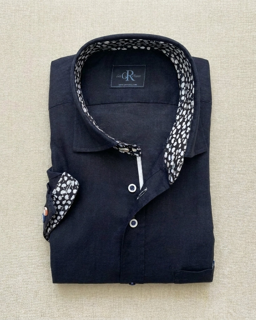 Folded navy shirt with patterned collar and pocket on a beige background