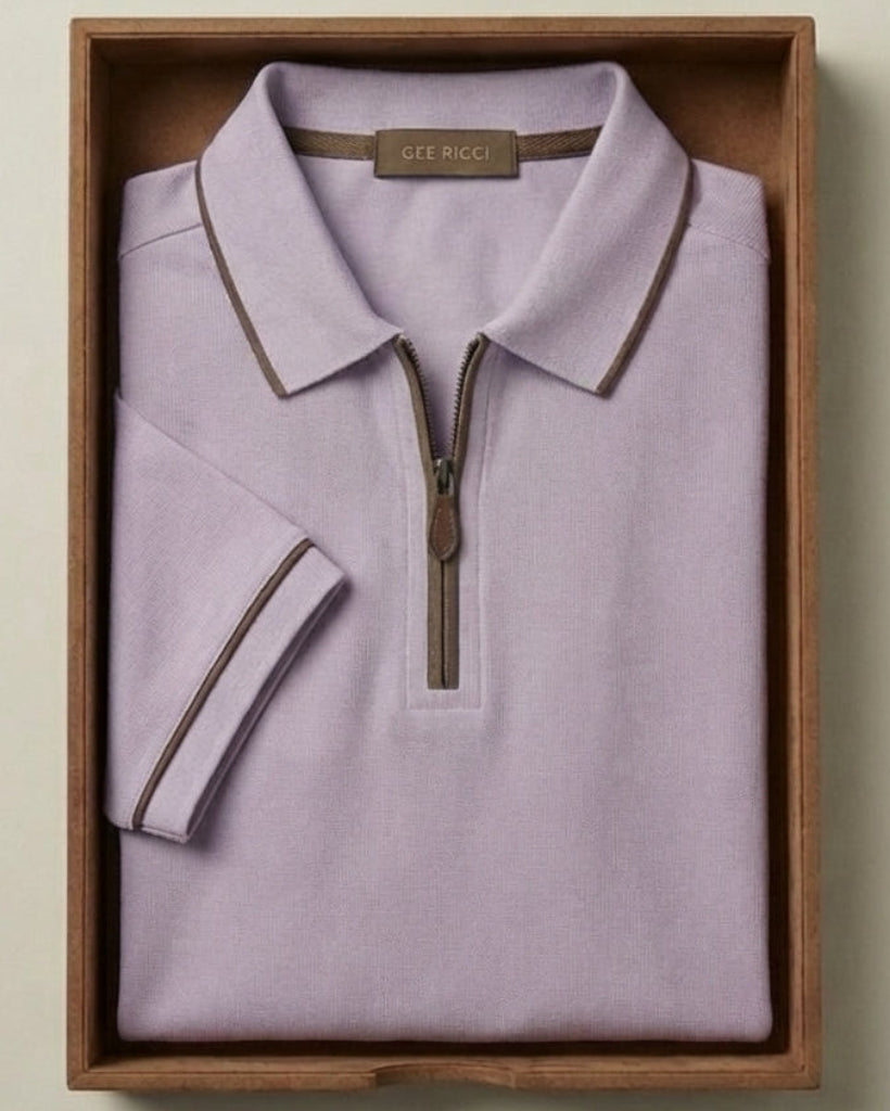 Folded light purple polo shirt with a zipper in a wooden box on a beige background