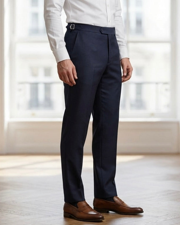 Person wearing navy pants and a white shirt in a bright room with large windows.
