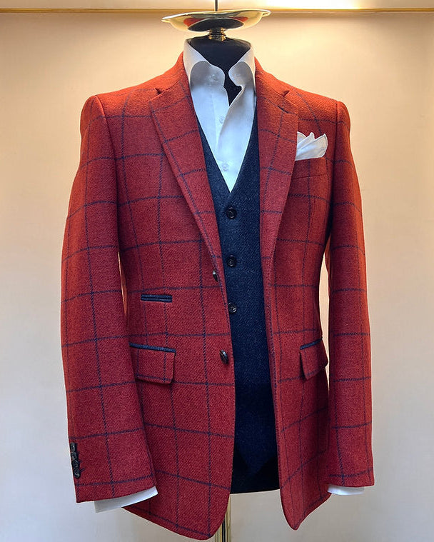 A red and blue wool blazer with a blue check design displayed on a mannequin. The blazer is two-buttoned and has a notch lapel.