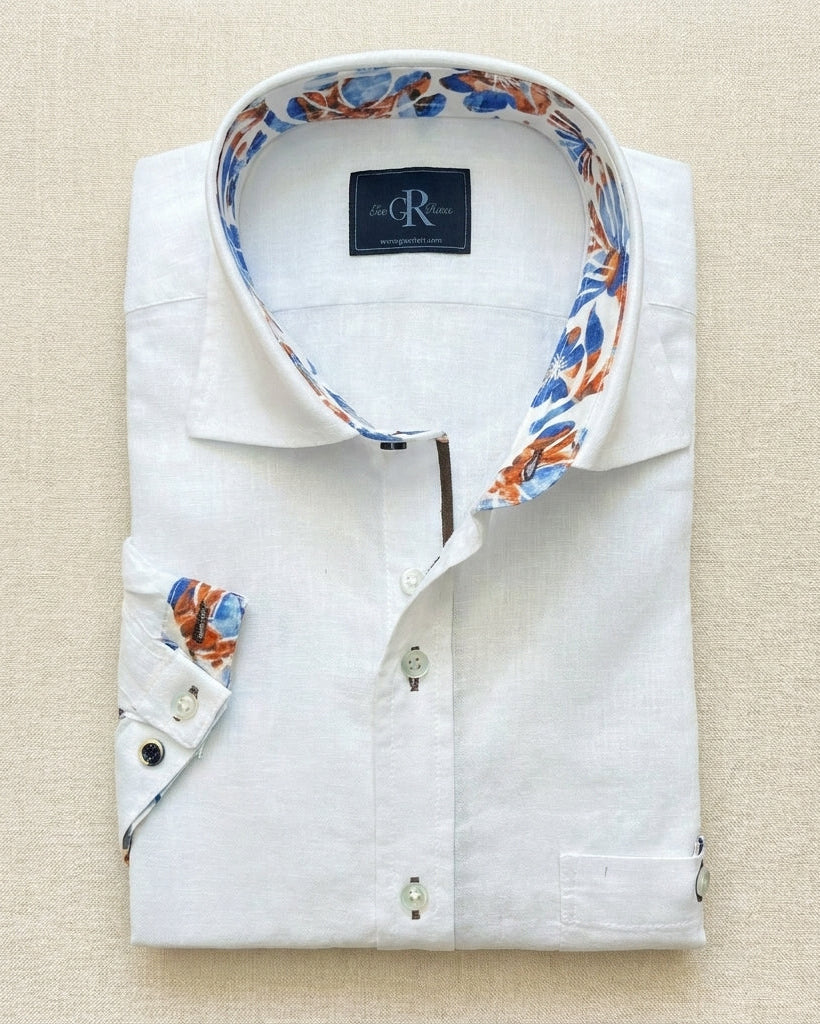 Folded white dress shirt with patterned collar and cuffs on a beige background