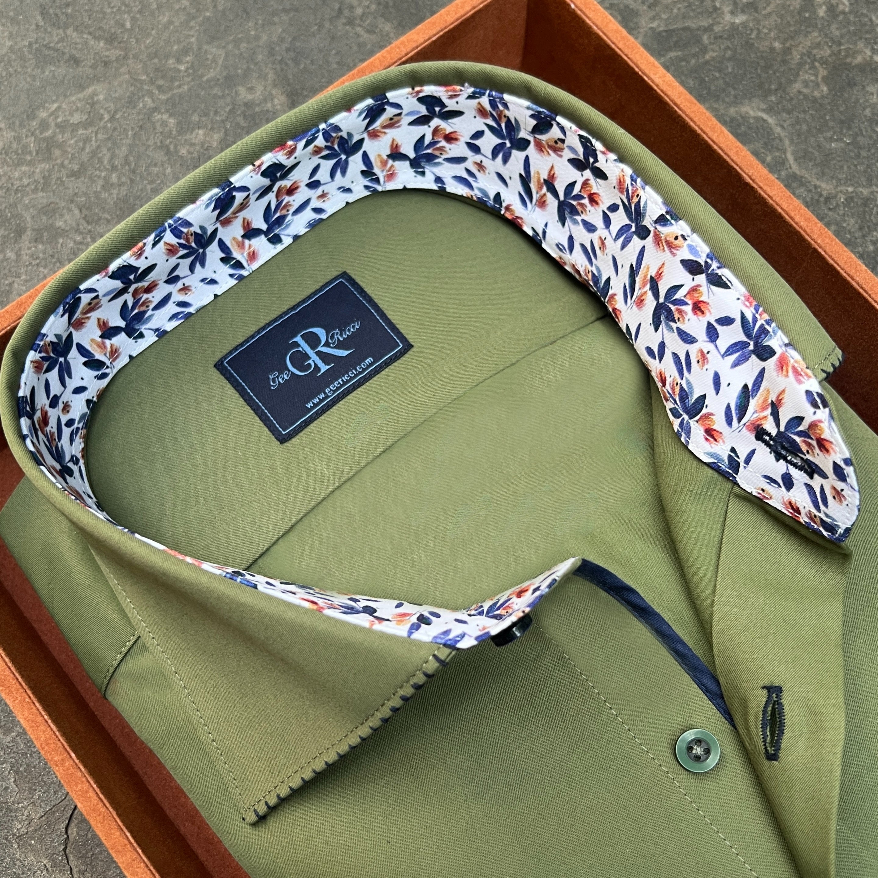 Green shirt with floral collar and 'R&G' label on a wooden surface