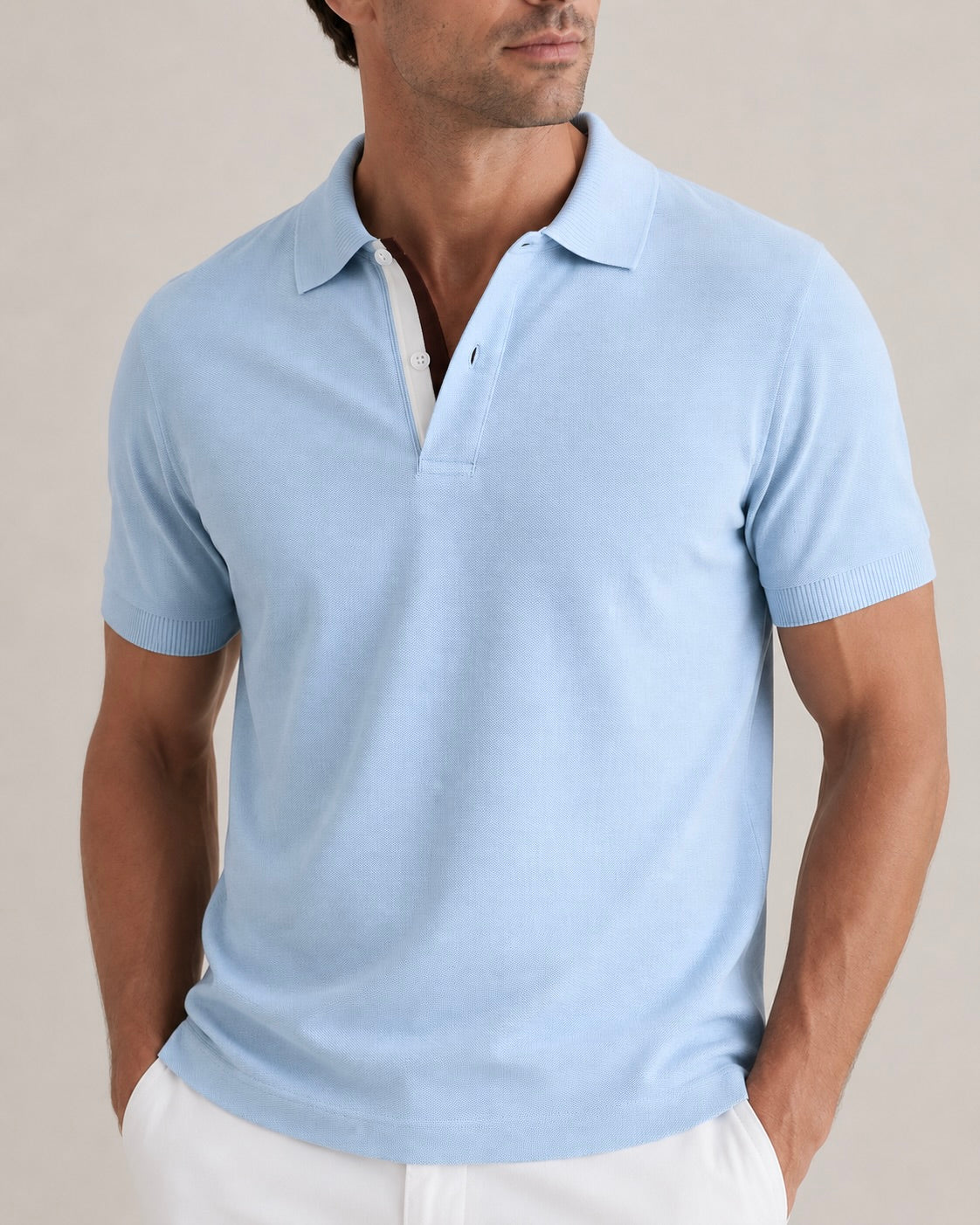 Man wearing a light blue polo shirt against a beige background