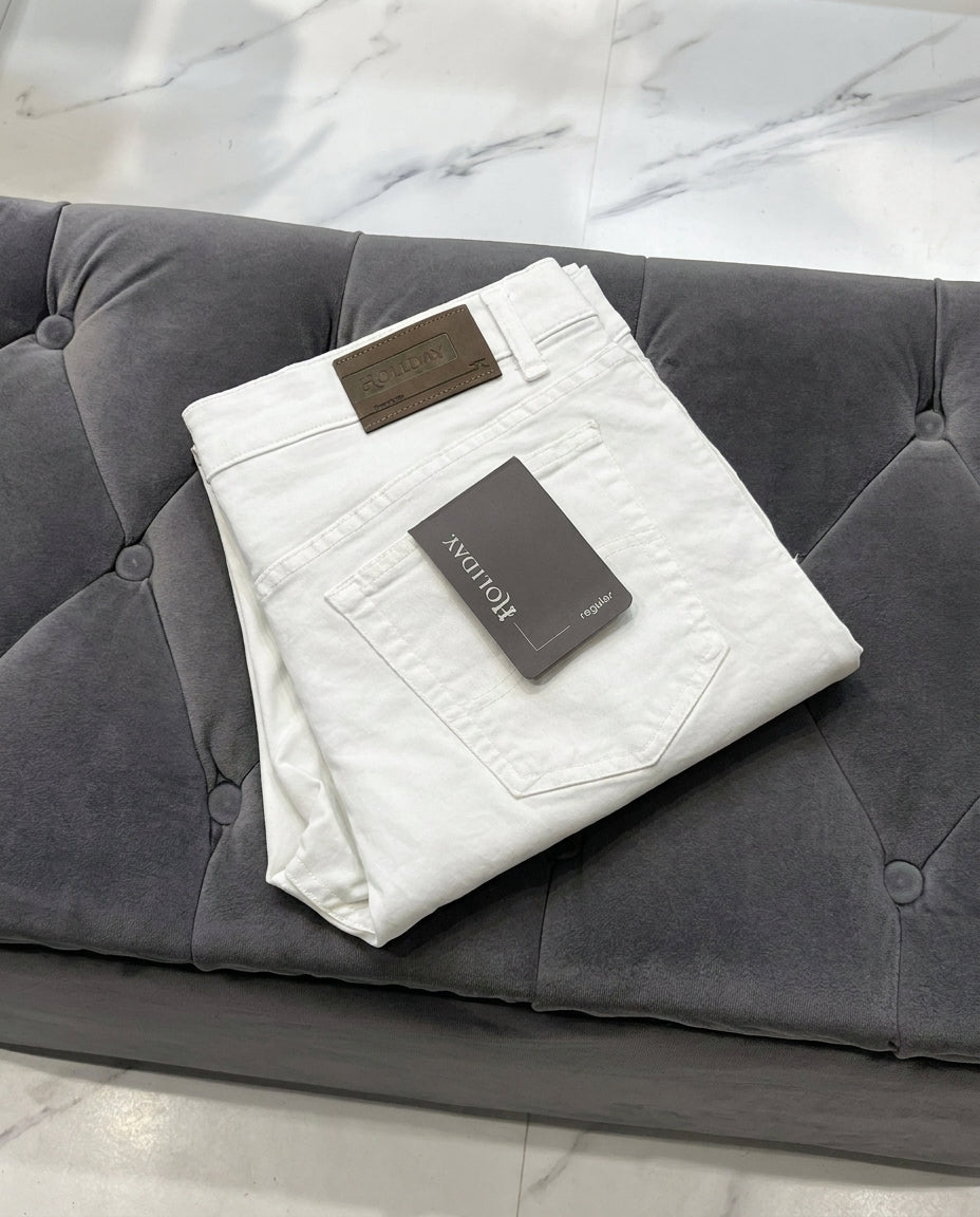 White jeans with a brand tag on a grey sofa