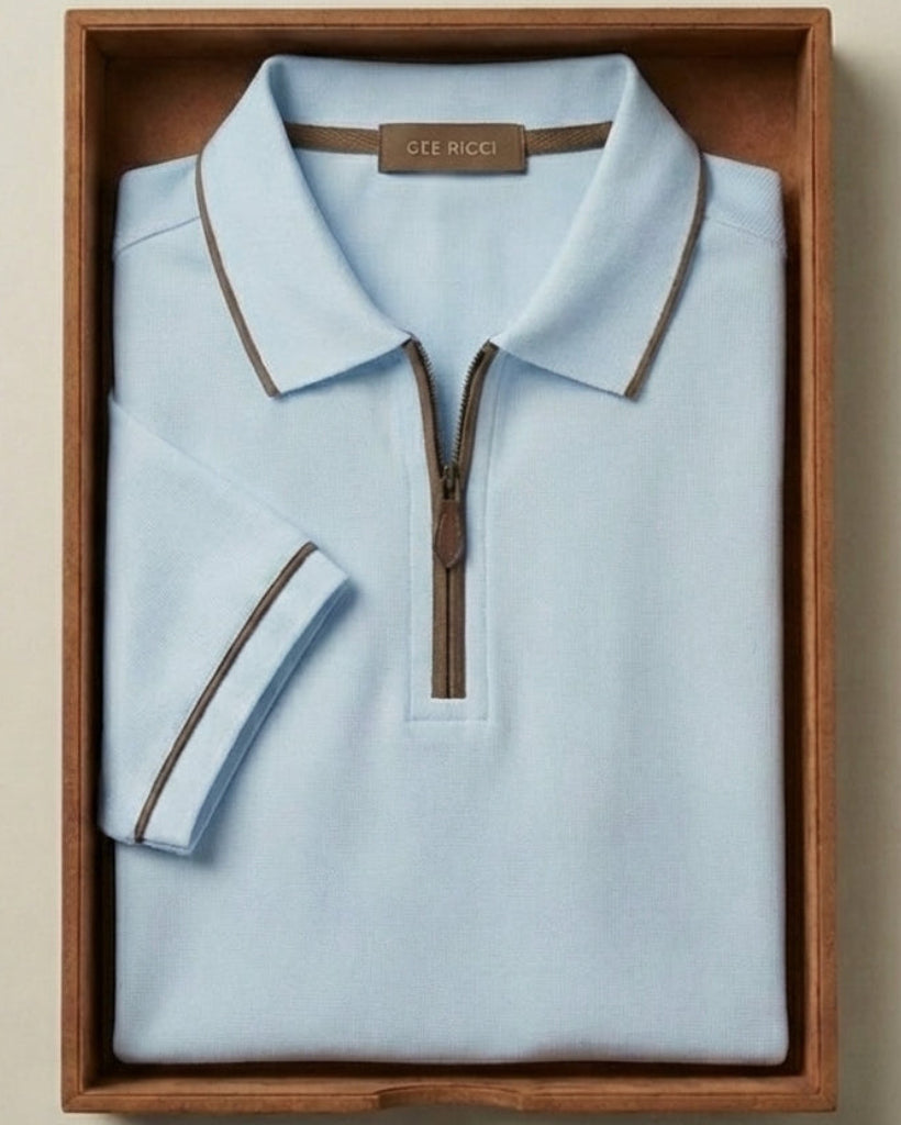 Light blue polo shirt with brown trim in a wooden box on a beige background