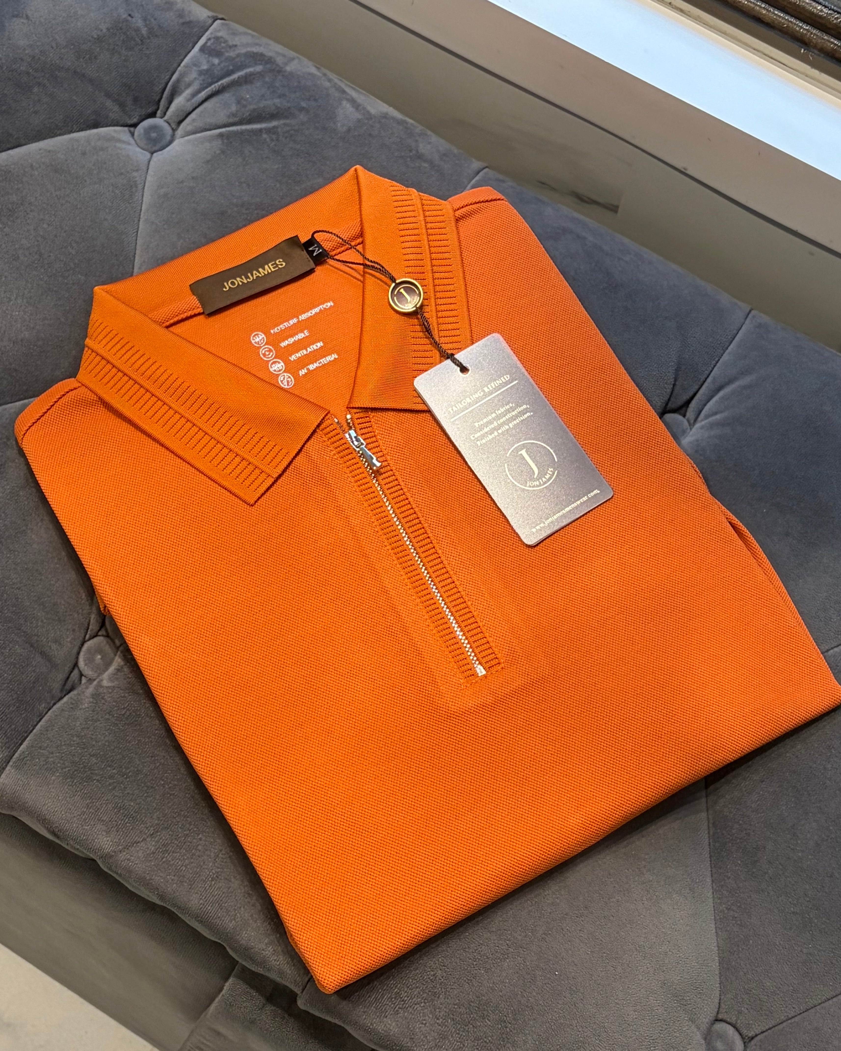 Orange shirt with a tag on a gray surface