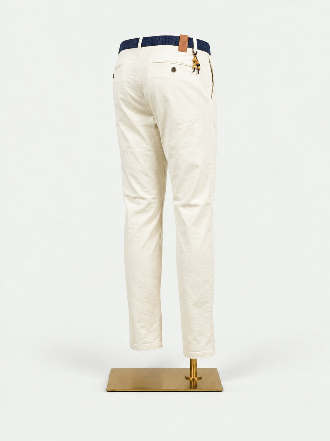 White pants with a blue belt on a mannequin against a beige background