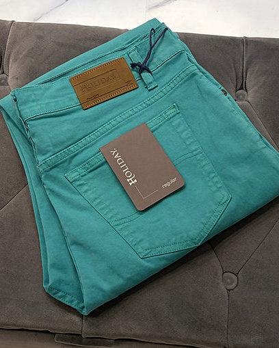 Folded teal pants with a tag on a gray couch