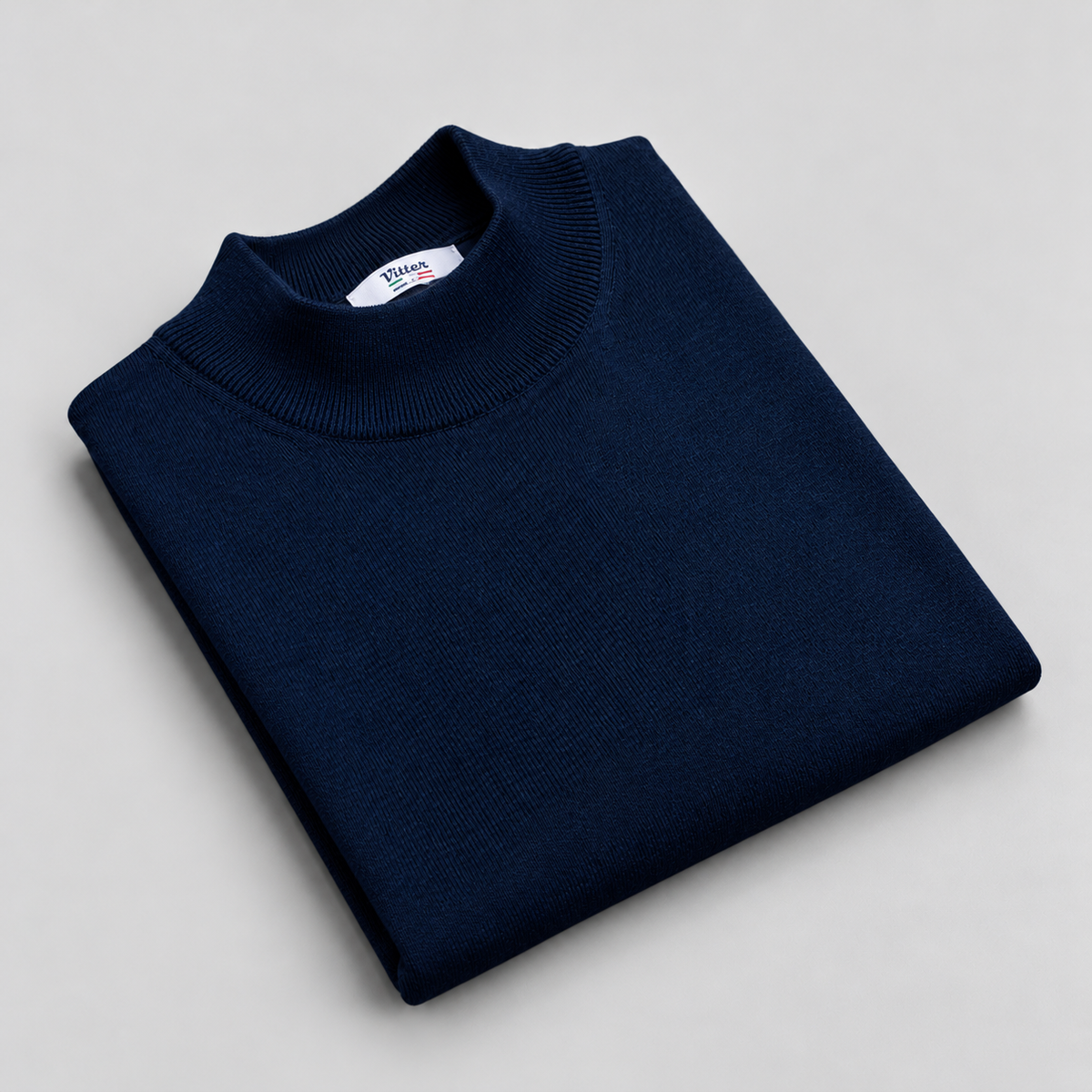 navy merino wool mock neck folded on a pale grey background