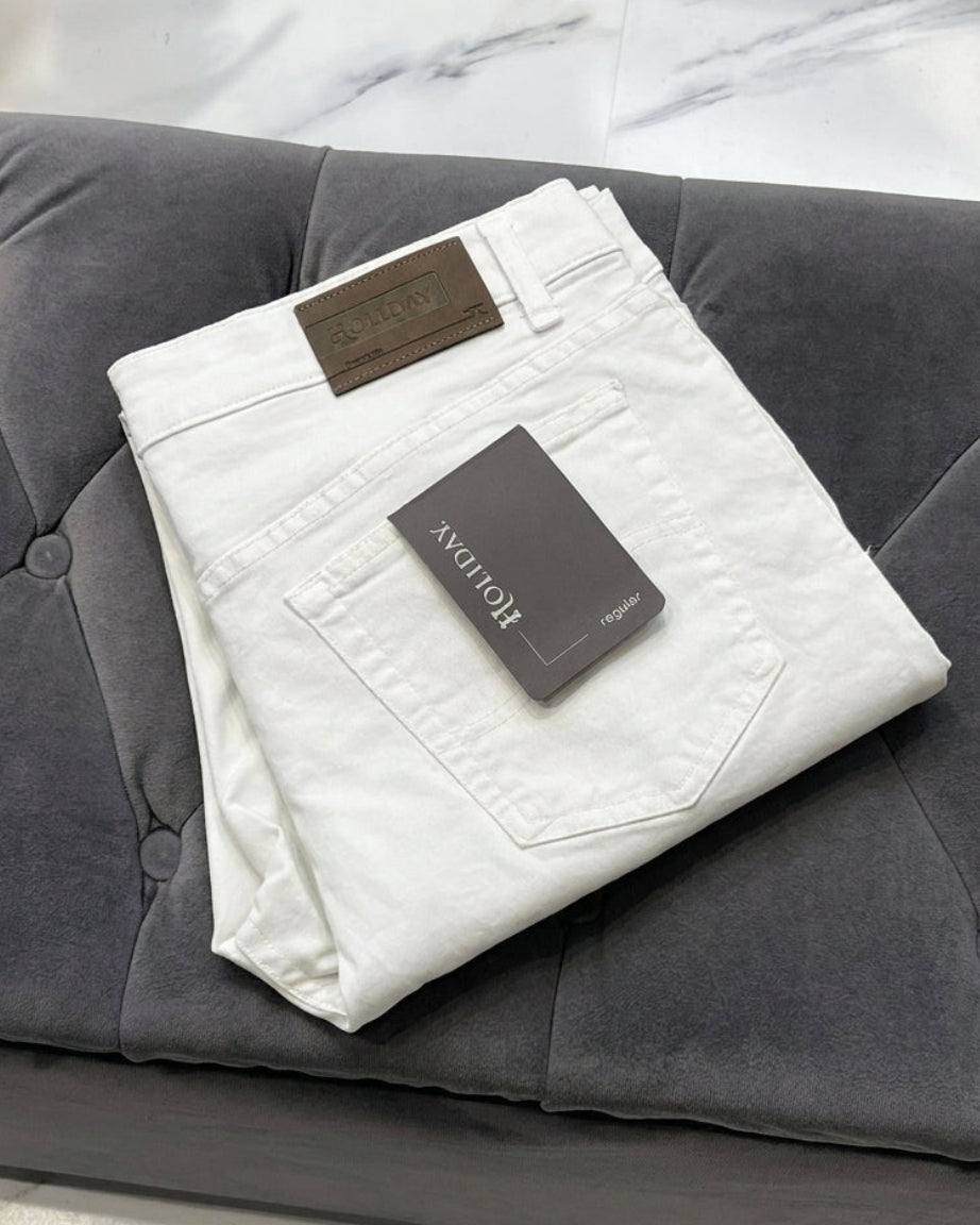White jeans with a brand tag on a grey sofa