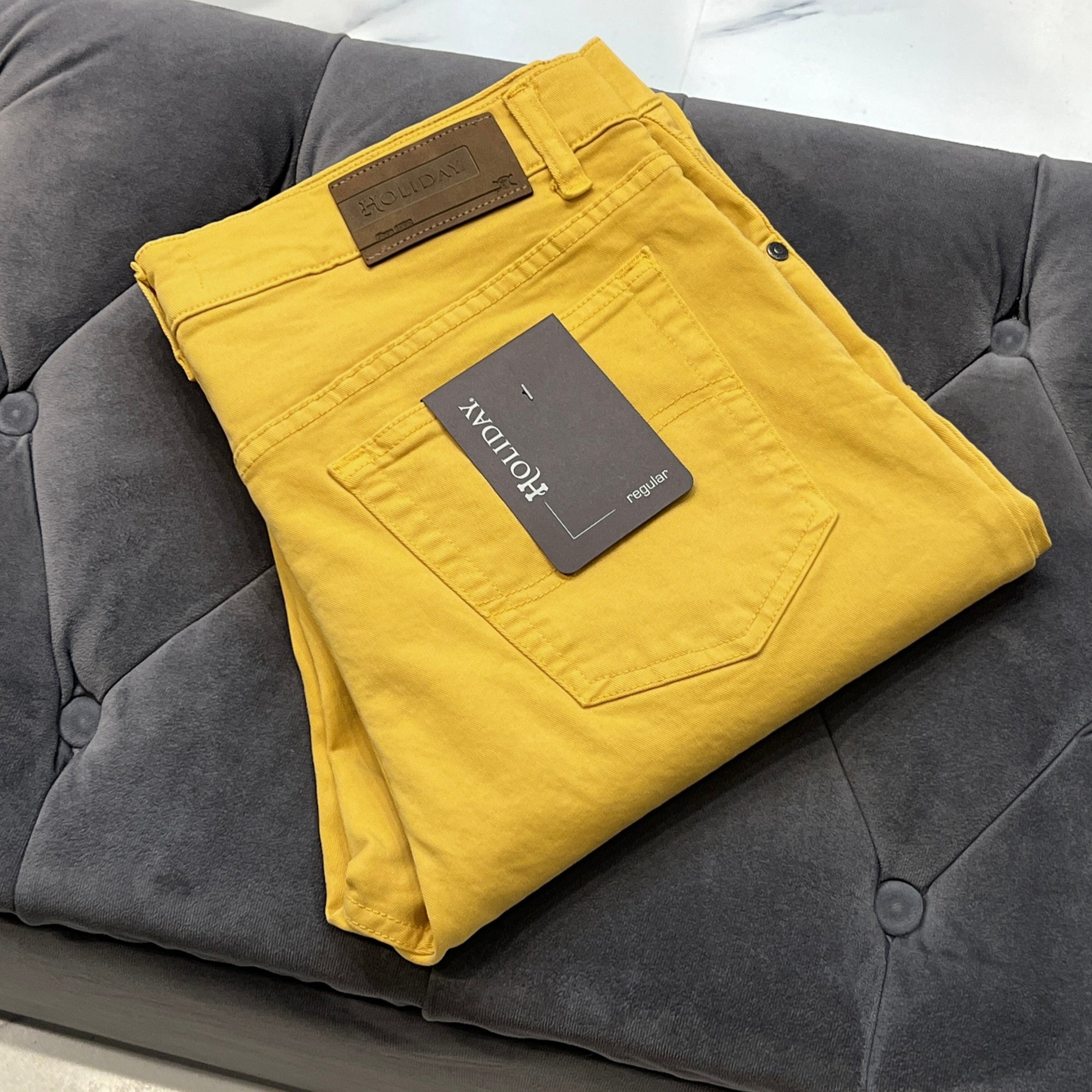 Folded yellow pants with a label on a gray couch
