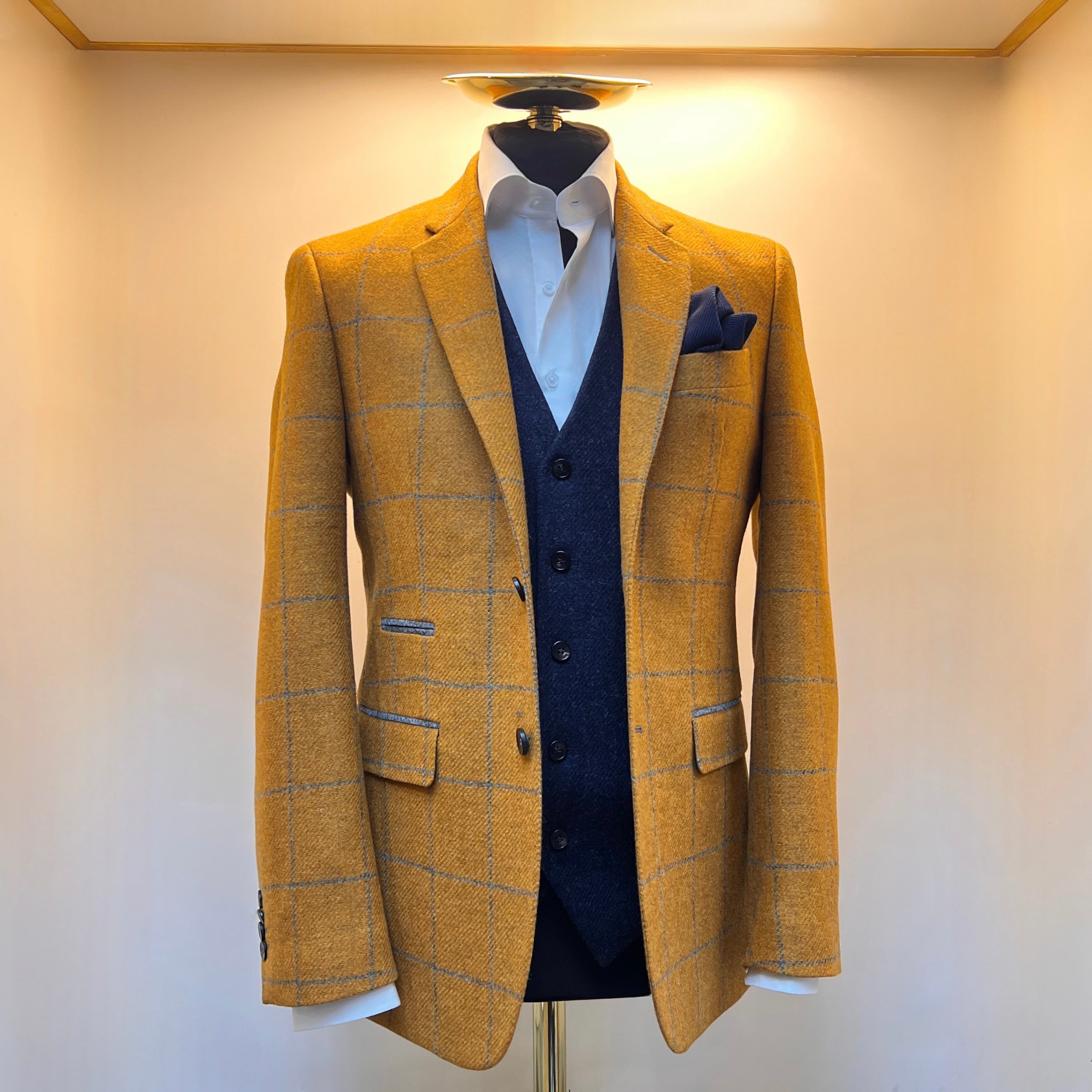 Men’s mustard grey overcheck blazer in virgin wool, made in Italy. Styled with a navy waistcoat and white shirt, featuring notched lapels and a tailored fit.