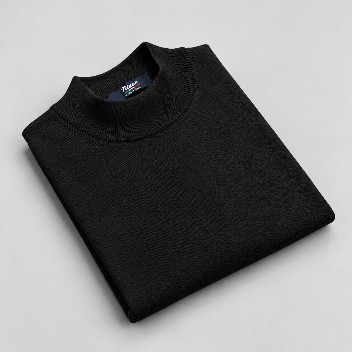 black merino wool mock neck folded on a pale grey background