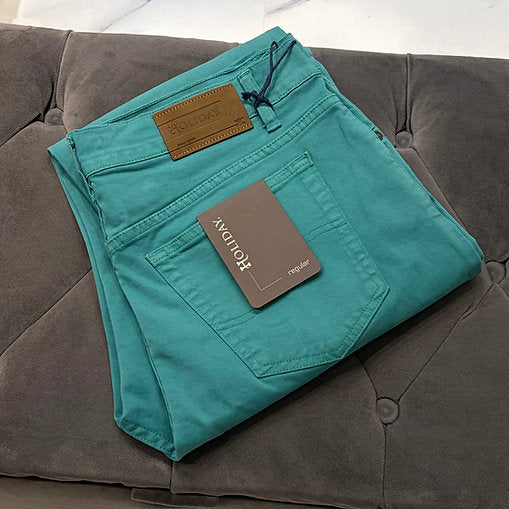 Folded teal pants with a tag on a gray couch